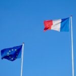 two flags flying next to each other in a blue sky